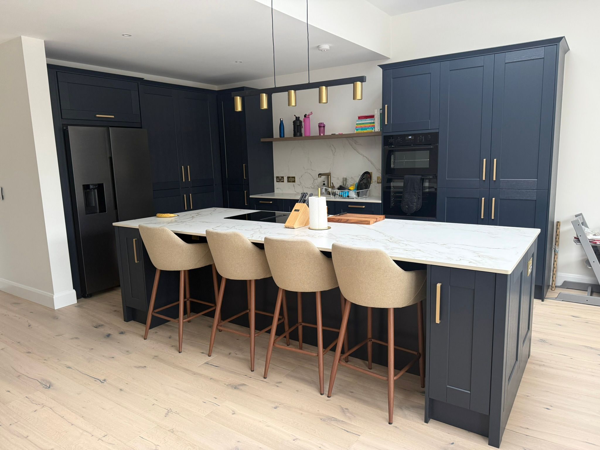Navy shaker kitchen with marble island and brass pendant lights
