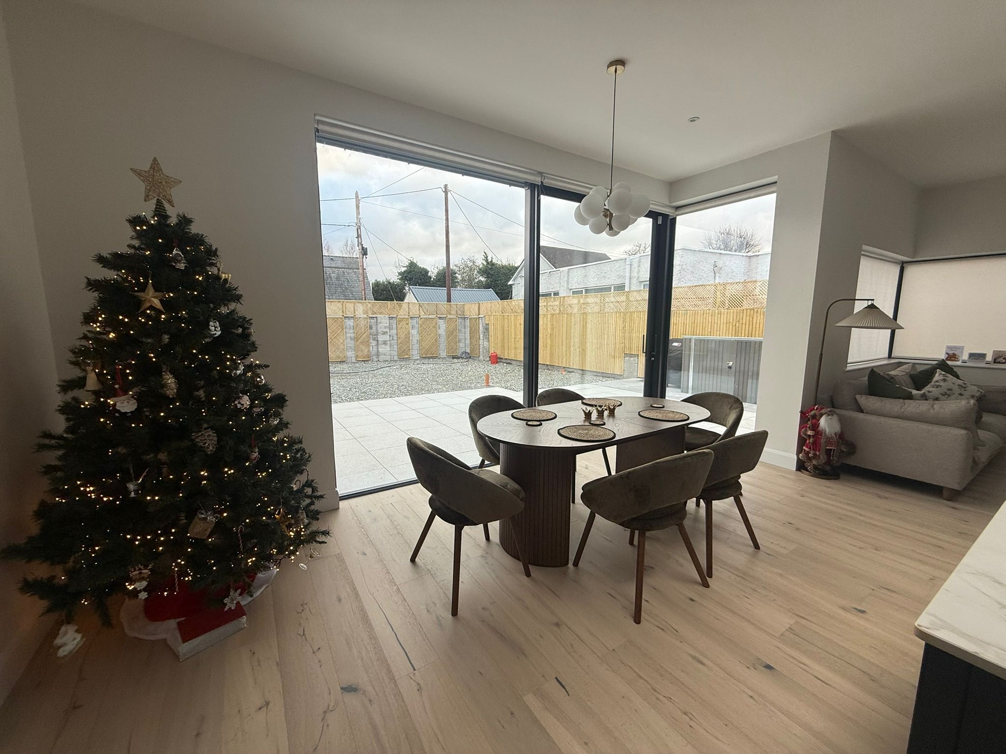 Open-plan dining area with large glass sliding doors and Christmas tree