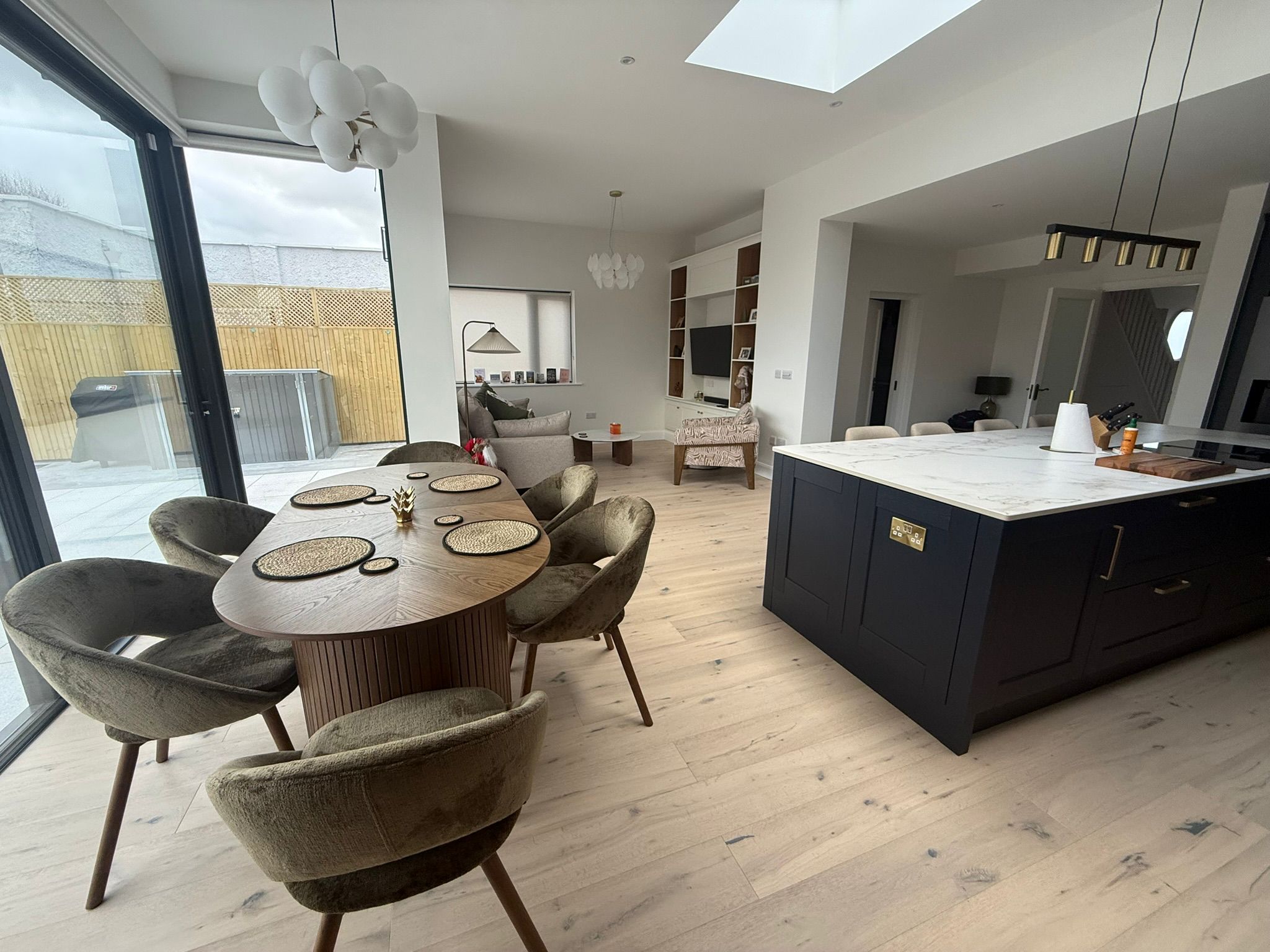 Open-plan kitchen dining and living space with skylight and full glazed wall