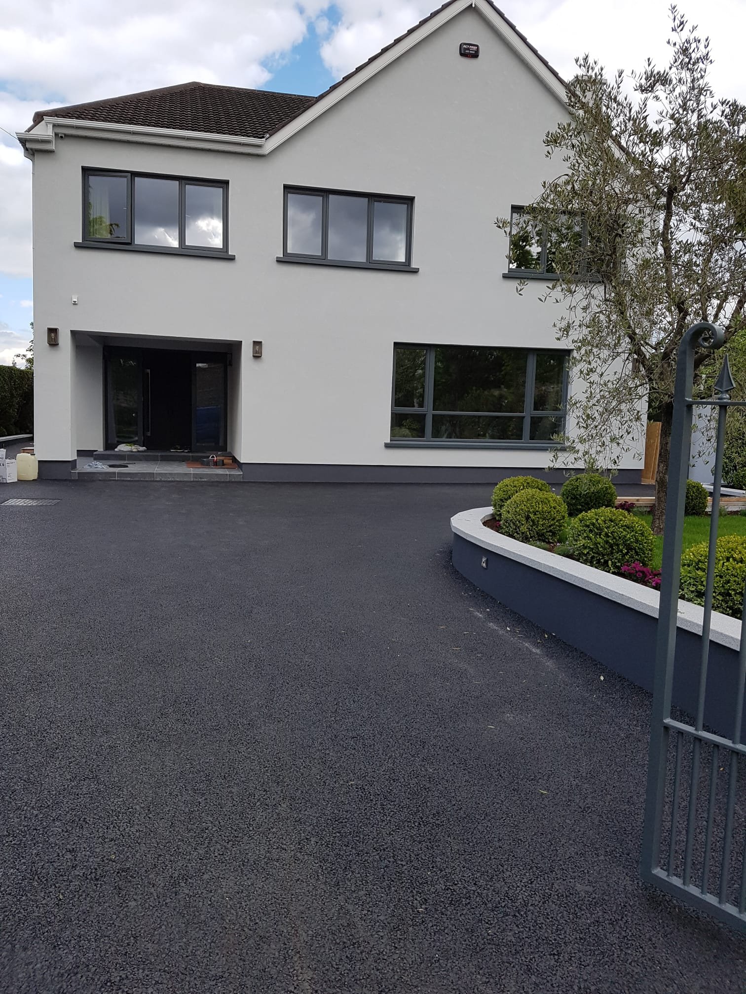 House front with new tarmac driveway, white render and landscaped planting